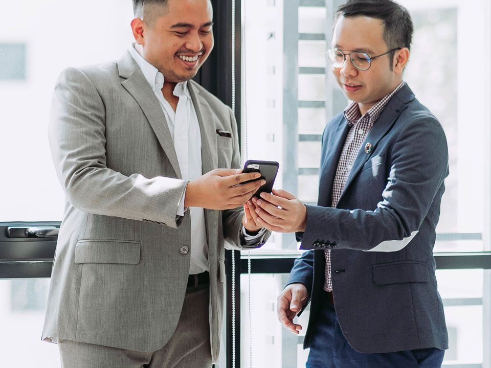 Two business professionals looking at a phone together in an office