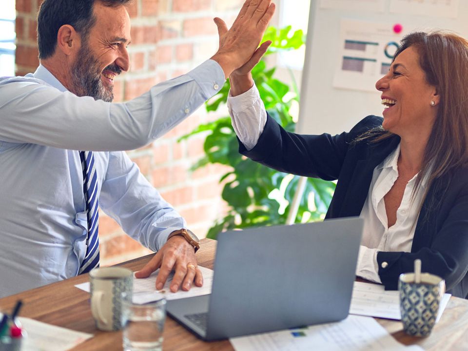 Coworkers giving a high five across a desk during a meeting