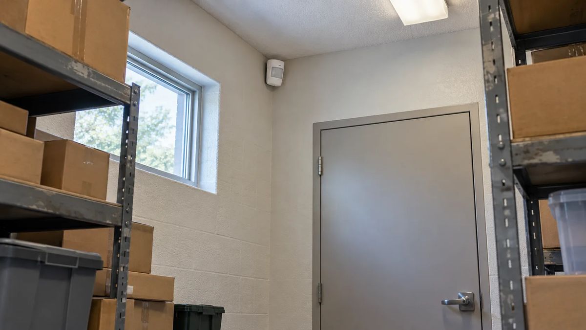 Motion detector above a stockroom door between shelves of supplies