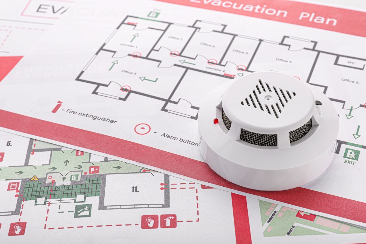 Smoke detector resting on a building fire evacuation plan
