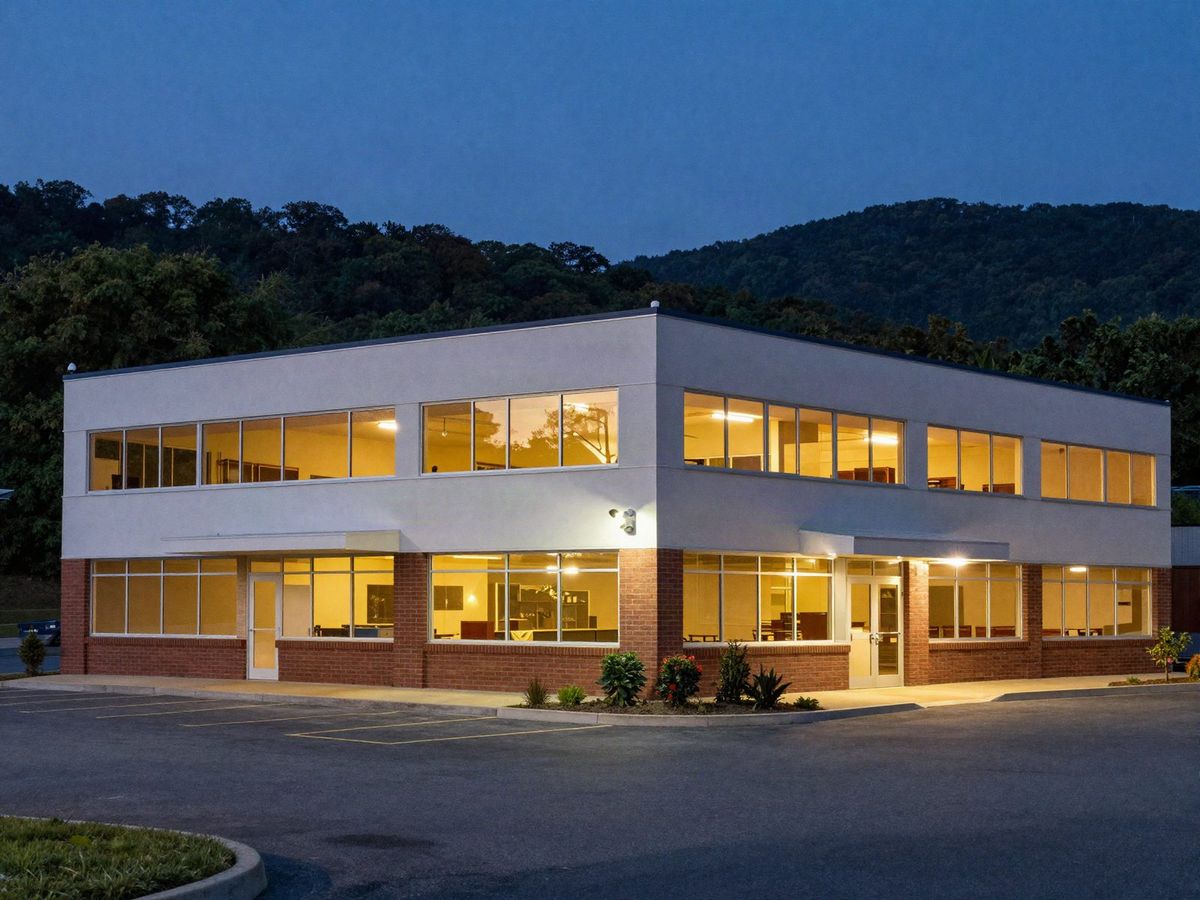 Two-story office building at night with security cameras covering a lit parking lot