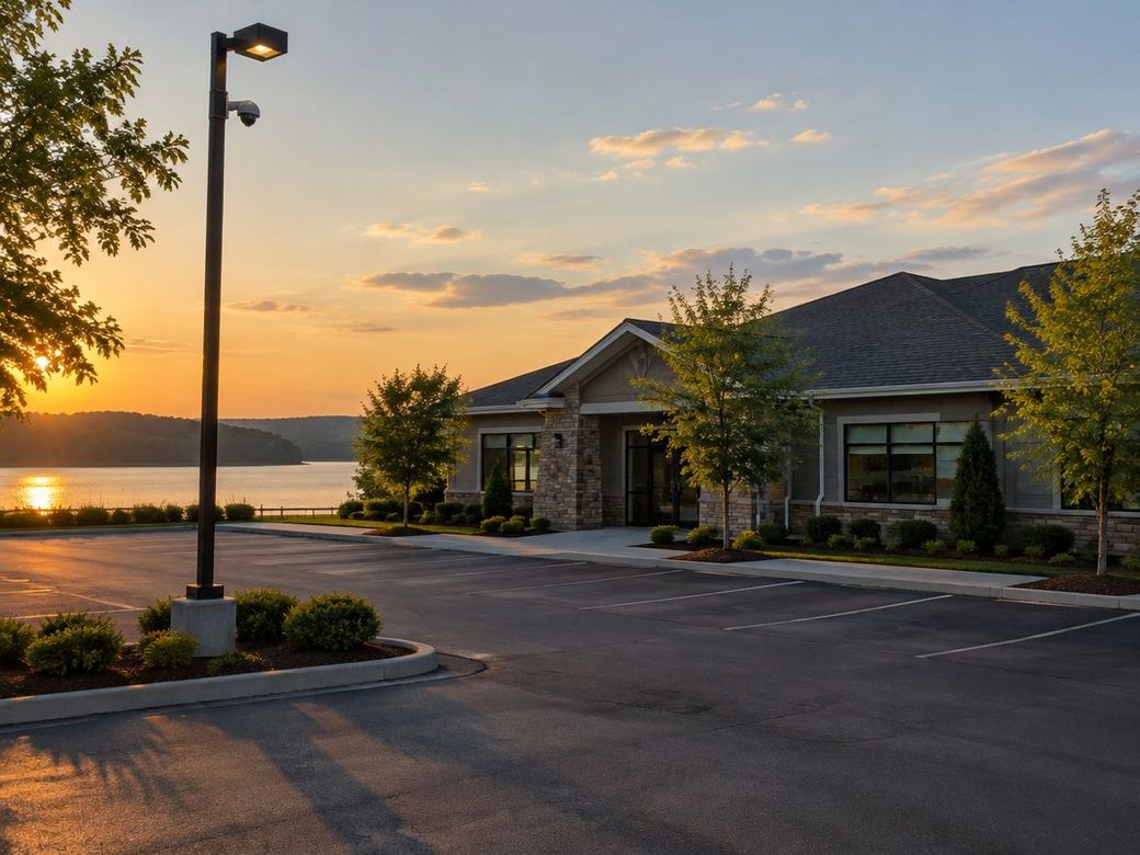 Lakeside office building and parking lot at sunset with a pole-mounted security camera