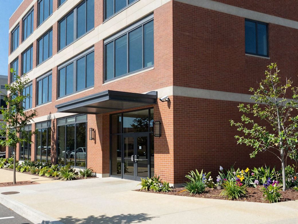 Brick and glass office building entrance with a security camera mounted beside the canopy