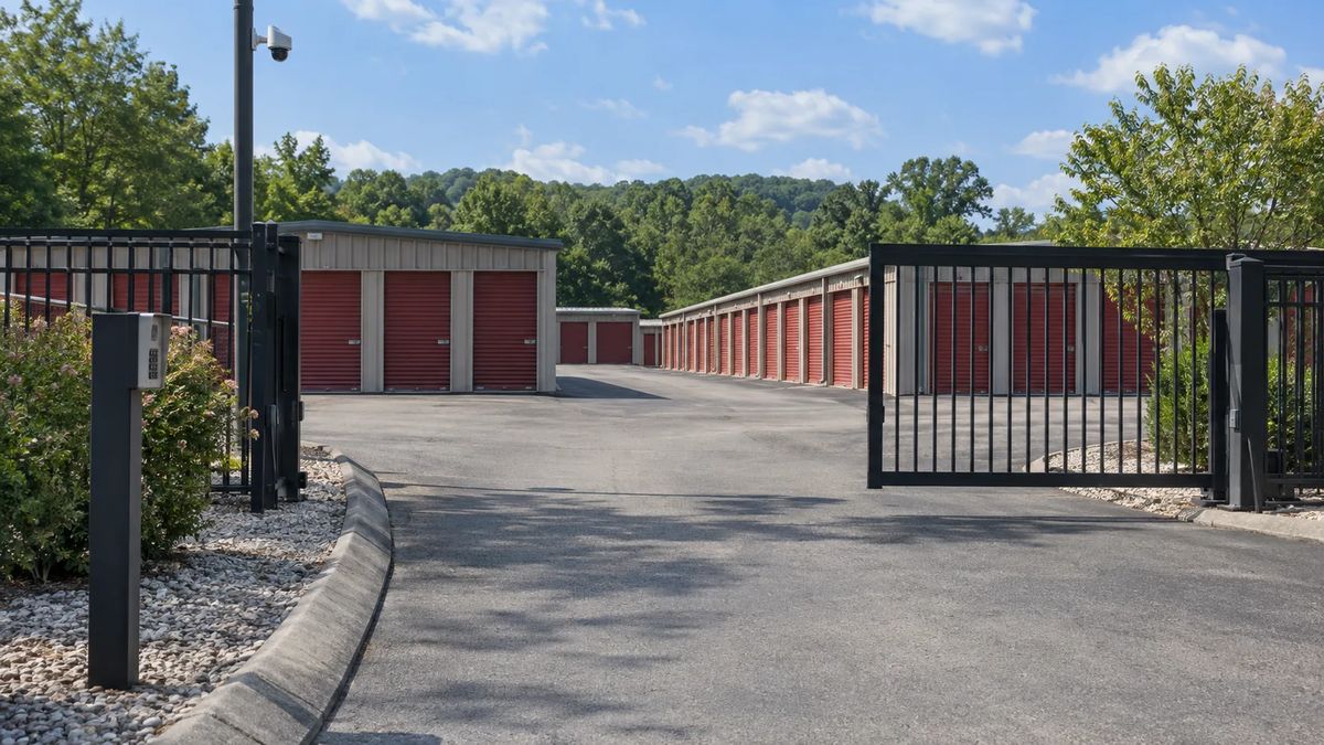 Self-storage entrance with an access pedestal, security camera, and rows of roll-up doors